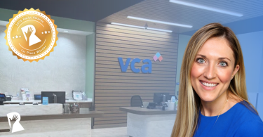 Smiling woman in blue at a VCA reception desk with an award badge overlay in the corner.